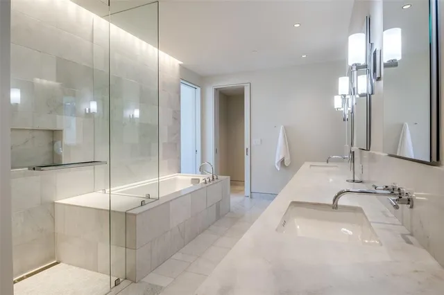 a bathroom with a sink double vanity granite tub shower and a mirror