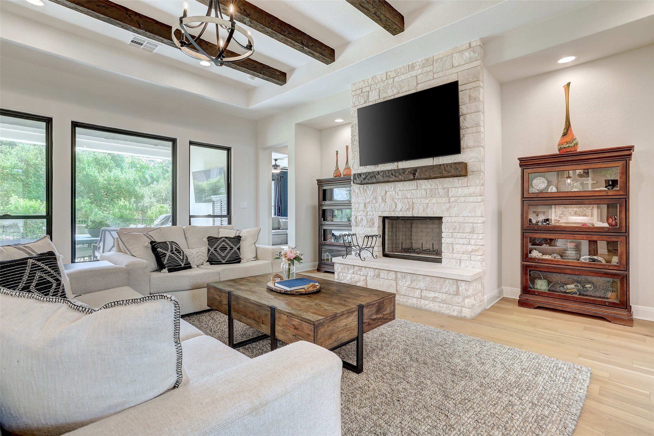 Living room with beam ceiling, wood floors, a fireplace, a chandelier, and recessed lighting