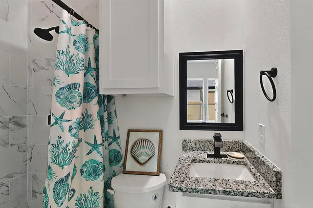 a bathroom with a granite countertop sink and a toilet