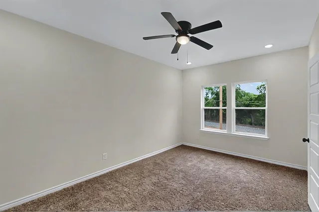 an empty room with window and ceiling fan