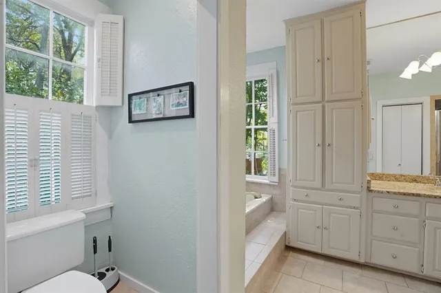 a bathroom with a granite countertop sink a toilet and a window