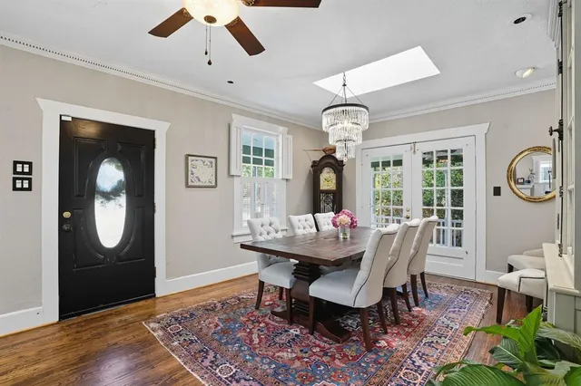a dining room with wooden floor a chandelier fan a wooden table and chairs