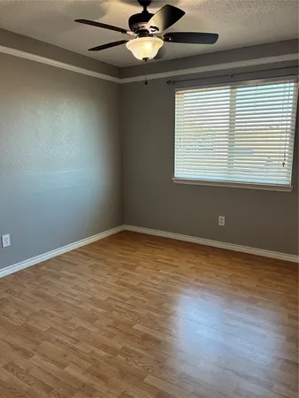 an empty room with wooden floor fan and windows