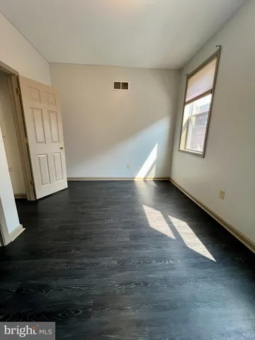 an empty room with wooden floor & windows