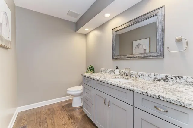 a bathroom with a granite countertop toilet sink and mirror