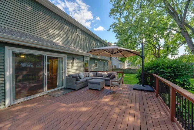 a view of a patio with couches and table and chairs under an umbrella with wooden floor