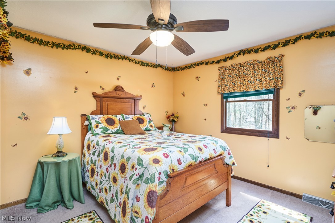 3097 Baughman Road Clinton, OH 44216 - Photo 12 of 27 Bedroom featuring a wood-finish bed frame, ceiling fan with integrated lighting, and a large window with wood-finish trim