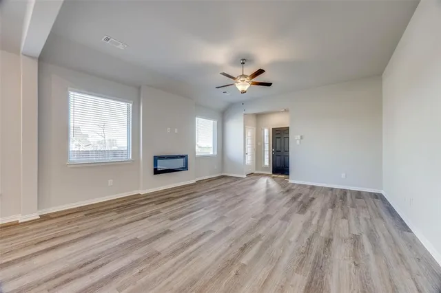 a view of an empty room with a window and wooden floor