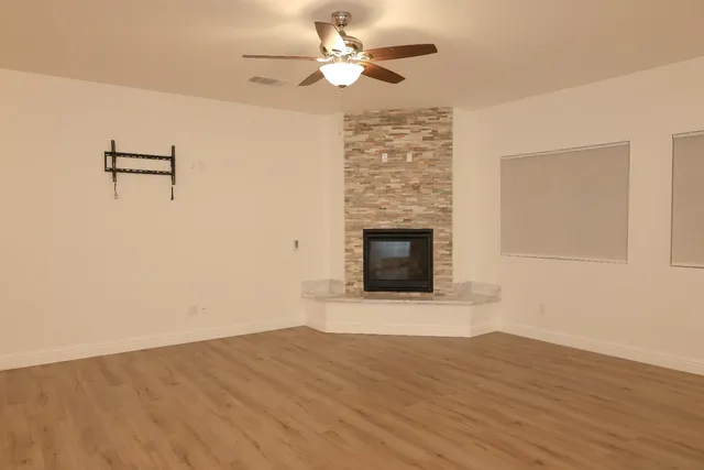 a view of empty room with wooden floor and fireplace
