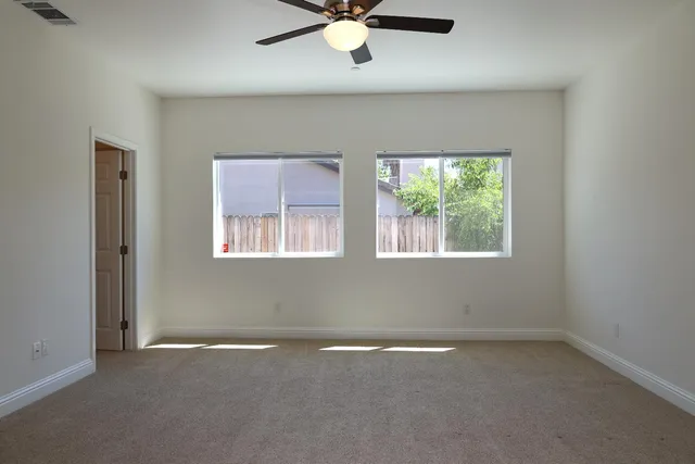 an empty room with windows and fan
