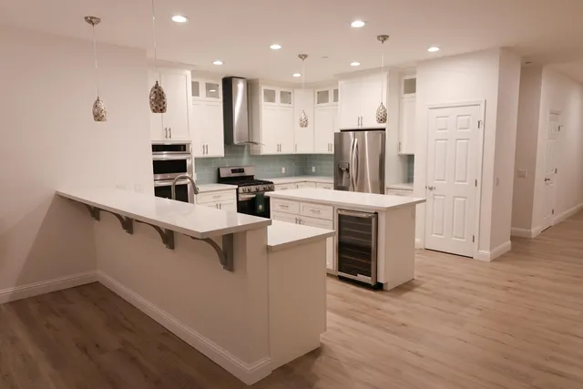 a kitchen with stainless steel appliances kitchen island granite countertop a stove a refrigerator a sink and a oven with wooden floor