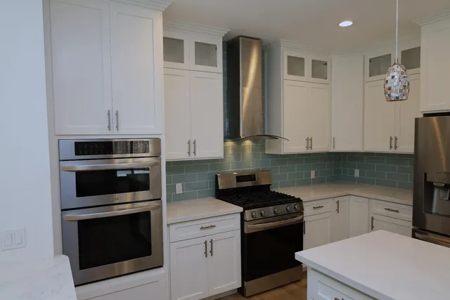 a kitchen with stainless steel appliances white cabinets and stove