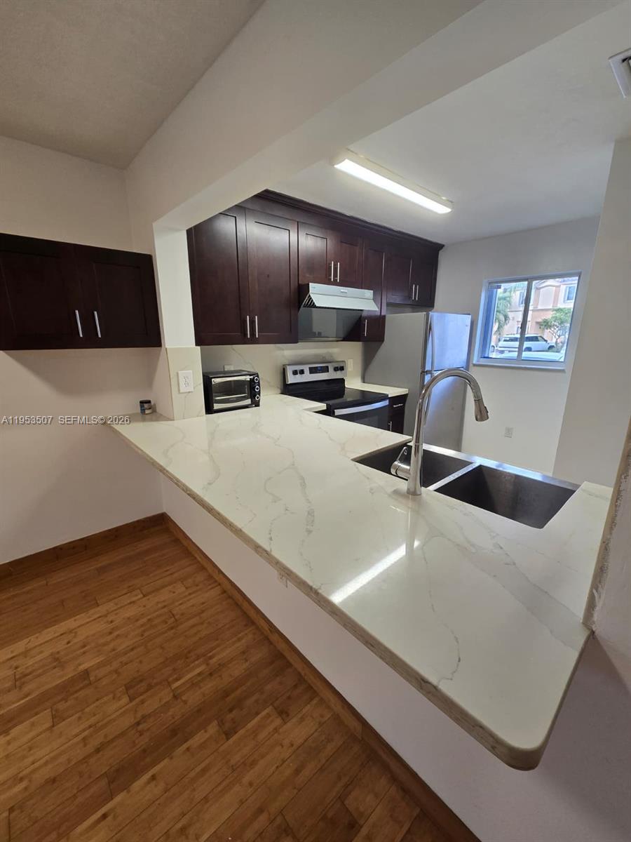 8394 Southwest 152nd Avenue, Unit 35 Miami, FL 33193 - Photo 7 of 24 a view of a kitchen with kitchen island a sink wooden floor and a refrigerator