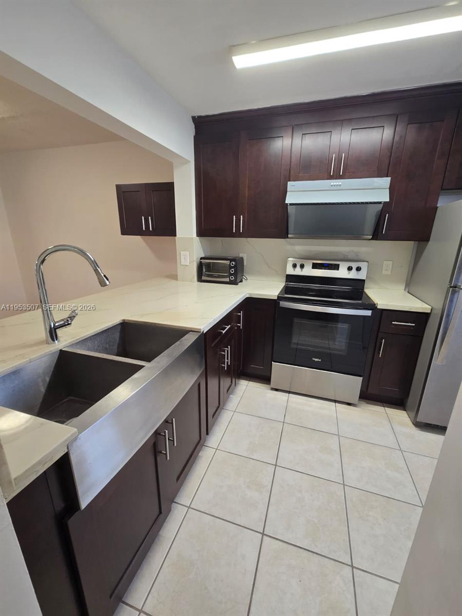 8394 Southwest 152nd Avenue, Unit 35 Miami, FL 33193 - Photo 8 of 24 a kitchen with stainless steel appliances a sink a stove a microwave and cabinets