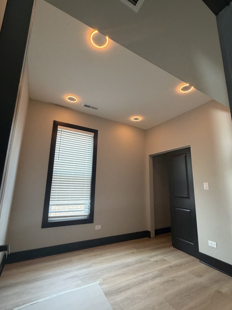 5252 West Berteau Avenue, Unit 2 Chicago, IL 60641 - Photo 9 of 11 a view of an empty room with wooden floor and a window