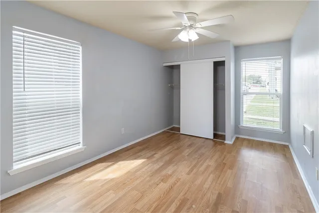 a view of empty room with wooden floor and ceiling fan