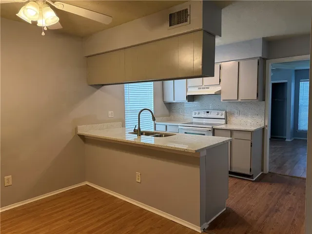a kitchen with stainless steel appliances granite countertop a sink dishwasher and stove with wooden cabinets