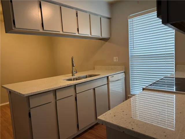 a kitchen with granite countertop a sink a stove and refrigerator