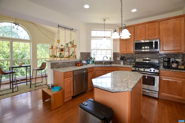 a kitchen with stainless steel appliances granite countertop a sink a stove a microwave a refrigerator and chairs