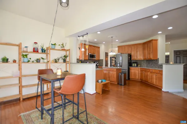 a kitchen with stainless steel appliances kitchen island granite countertop a dining table chairs and a refrigerator