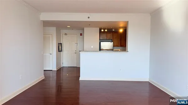 a view of a hallway with wooden floor and a bathroom