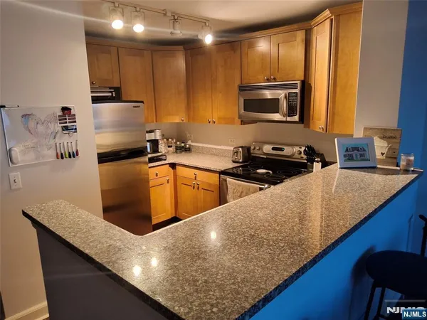 a kitchen with granite countertop a sink a counter top space cabinets stainless steel appliances and a counter top space