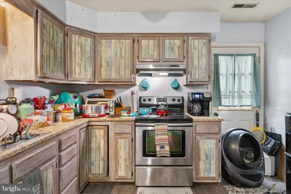 a kitchen with kitchen island granite countertop a stove a sink dishwasher and white cabinets with wooden floor