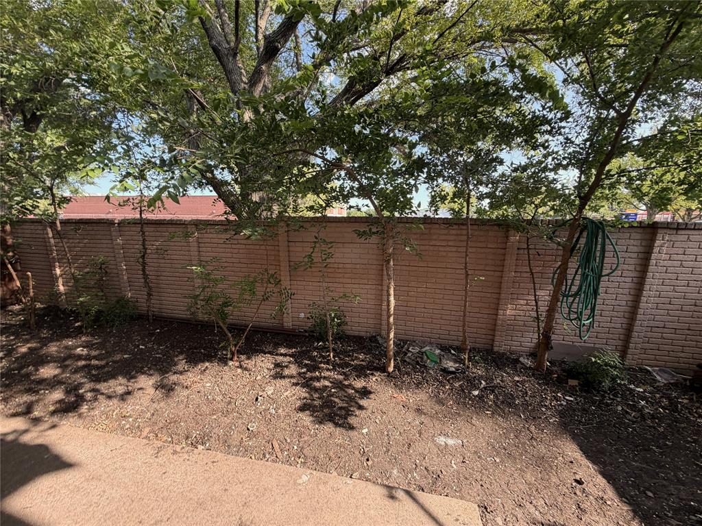 18240 Midway Road, Unit 206 Dallas, TX 75287 - Photo 8 of 16 Privacy brick wall bordering a landscaped area with mature trees and ground cover