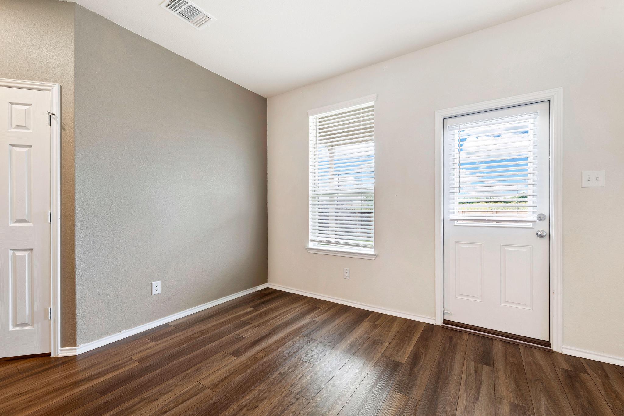 217 Innisfree Road Jarrell, TX 76537 - Photo 17 of 39 Rich hardwood-style flooring extends across this versatile interior space, illuminated by natural light from the exterior door.