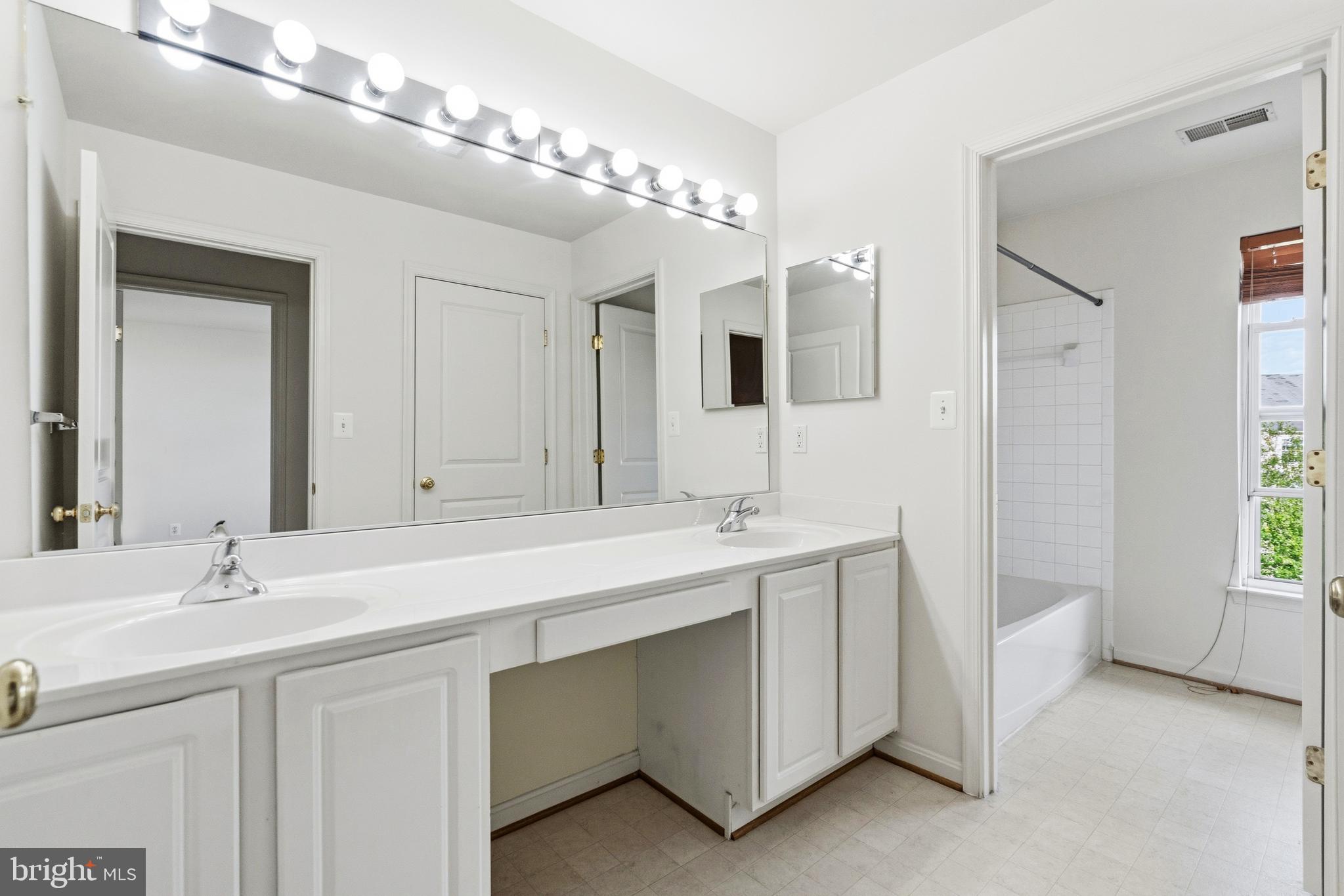 9227 Ribbon Falls Loop Bristow, VA 20136 - Photo 50 of 53 a bathroom with a double vanity sink a mirror and a bathtub