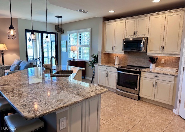 10470 Casella Way, Unit 102 Fort Myers, FL 33913 - Photo 4 of 18 a kitchen with kitchen island granite countertop a stove sink and microwave