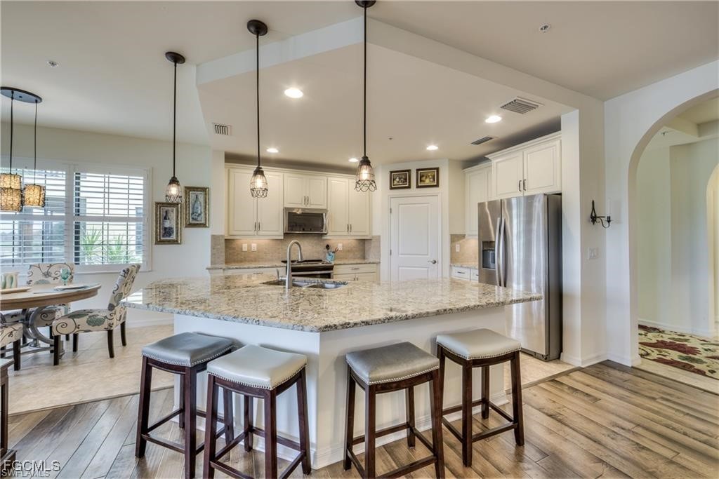 10470 Casella Way, Unit 102 Fort Myers, FL 33913 - Photo 5 of 18 a kitchen with stainless steel appliances kitchen island granite countertop a table chairs and a refrigerator