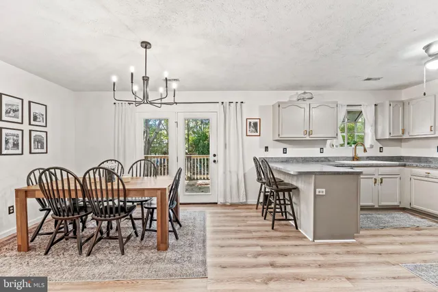 a kitchen with stainless steel appliances granite countertop a dining table chairs refrigerator sink and cabinets