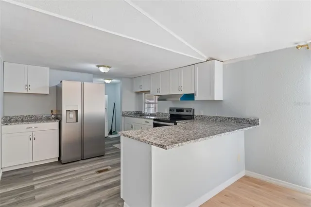 a kitchen with stainless steel appliances granite countertop a refrigerator a stove and a sink