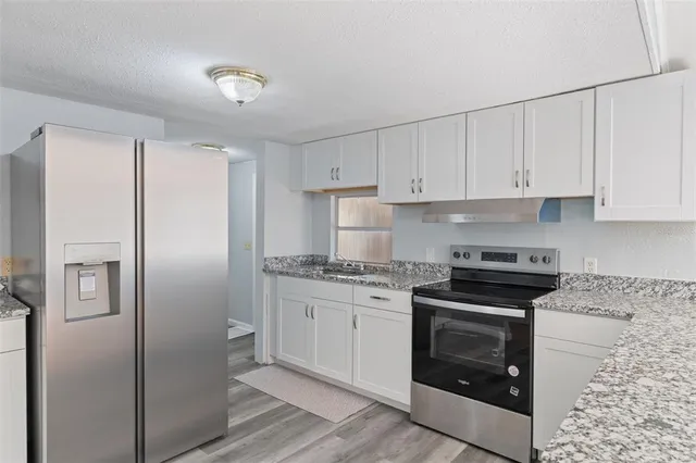 a kitchen with stainless steel appliances granite countertop a refrigerator sink and stove