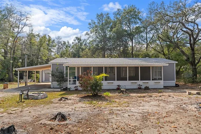 a front view of house with yard seating and covered with trees