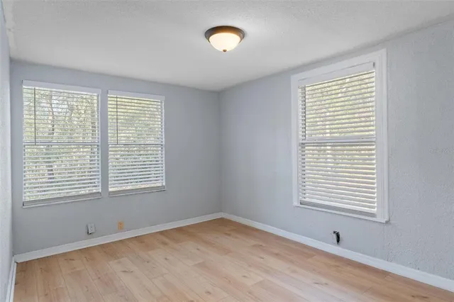a view of an empty room with a window and wooden floor