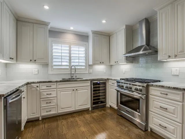 a kitchen with stainless steel appliances granite countertop a stove and white cabinets