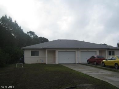 941 Homestead Road South, Unit 941/943 Lehigh Acres, FL 33974 - Photo 1 of 19 a front view of a house with a garden