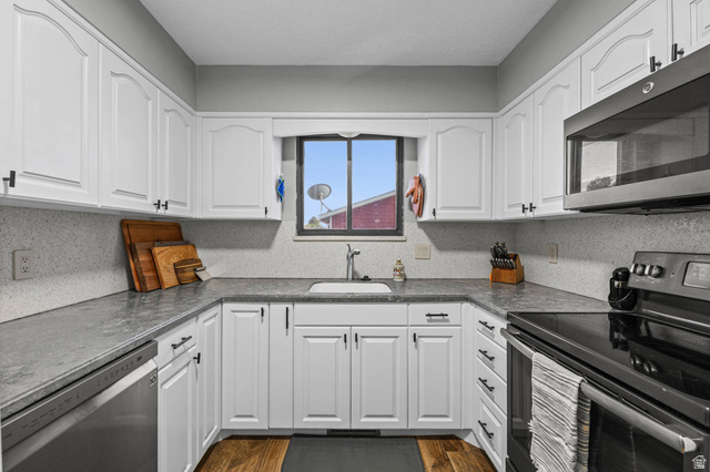 5896 South 3950th Street West Roy, UT 84067 - Photo 9 of 29 Kitchen featuring stainless steel appliances, white cabinets, dark countertops, and dark wood-type flooring