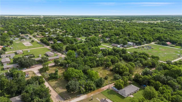 an aerial view of residential houses with outdoor space and trees
