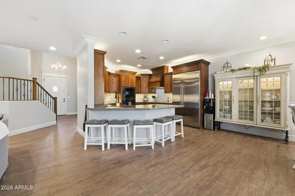 a kitchen with stainless steel appliances granite countertop a stove top oven a sink a dining table and chairs with wooden floor