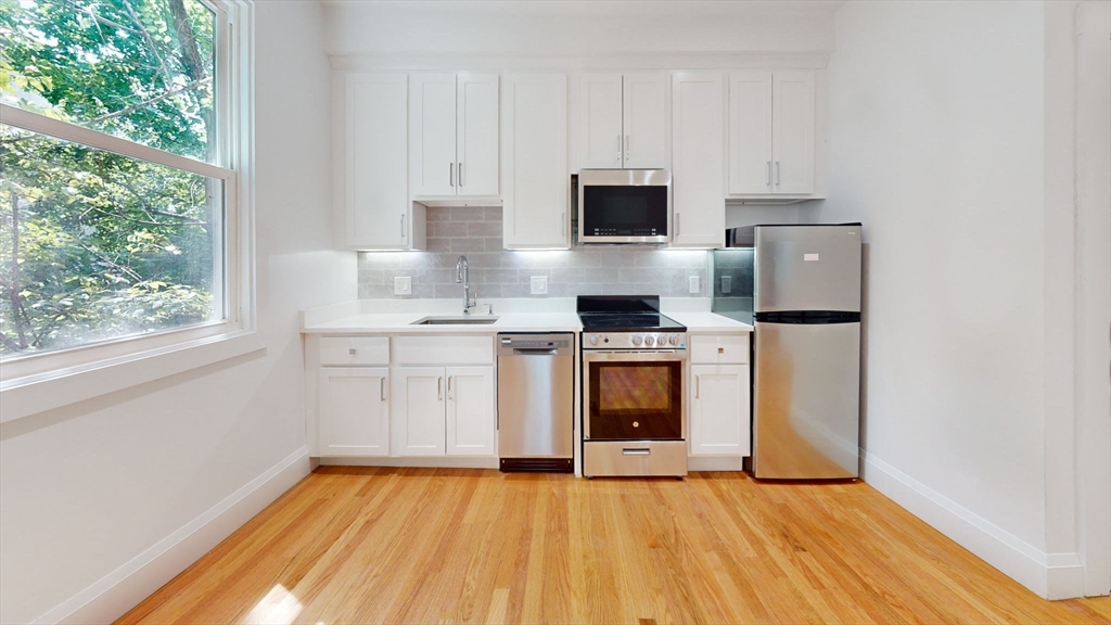 21 Regent Circle, Unit 3 Brookline, MA 02445 - Photo 7 of 21 a kitchen with stainless steel appliances a white stove top oven and white cabinets