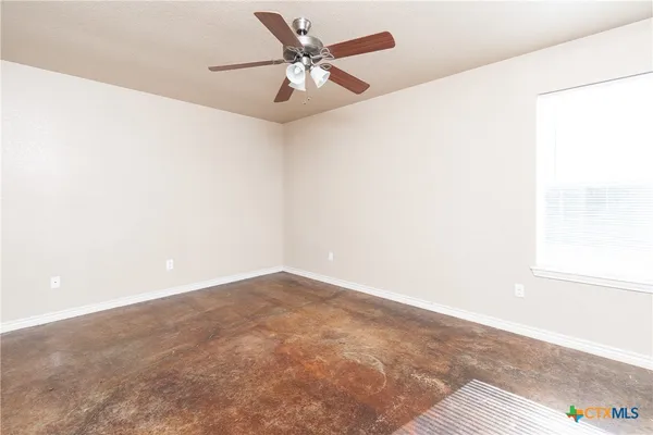 an empty room with a window and a ceiling fan