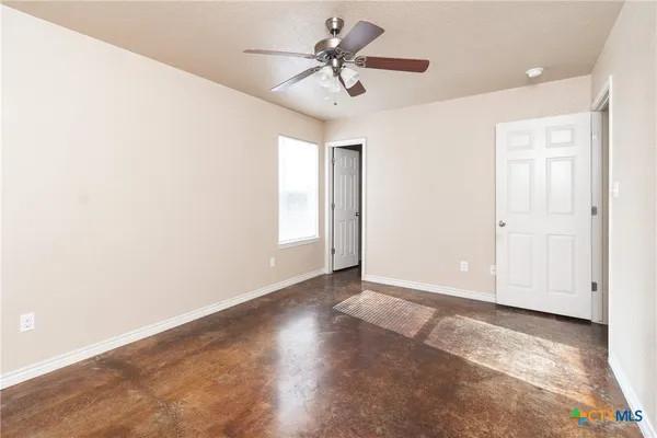 an empty room with windows and fan