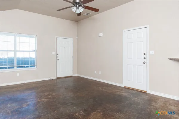 an empty room with a window and a ceiling fan