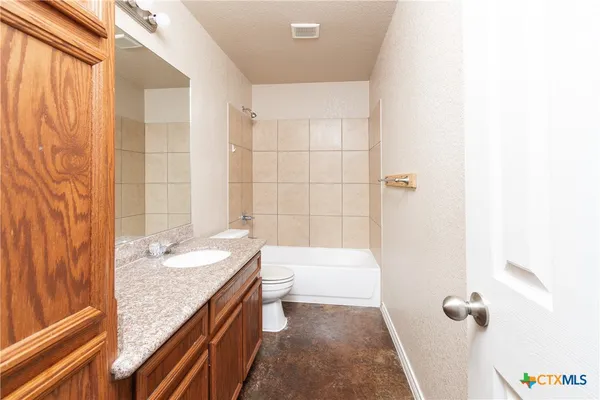 a bathroom with a granite countertop sink a toilet and shower