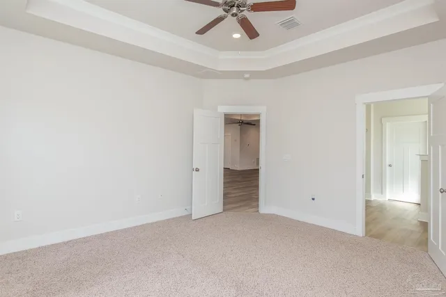 an empty room with a ceiling fan and carpet