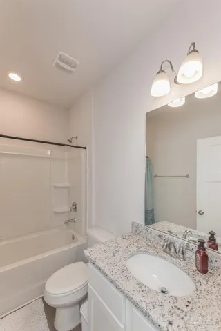 a bathroom with a granite countertop sink a toilet and bathtub