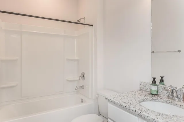 a bathroom with a granite countertop bathtub sink vanity and toilet